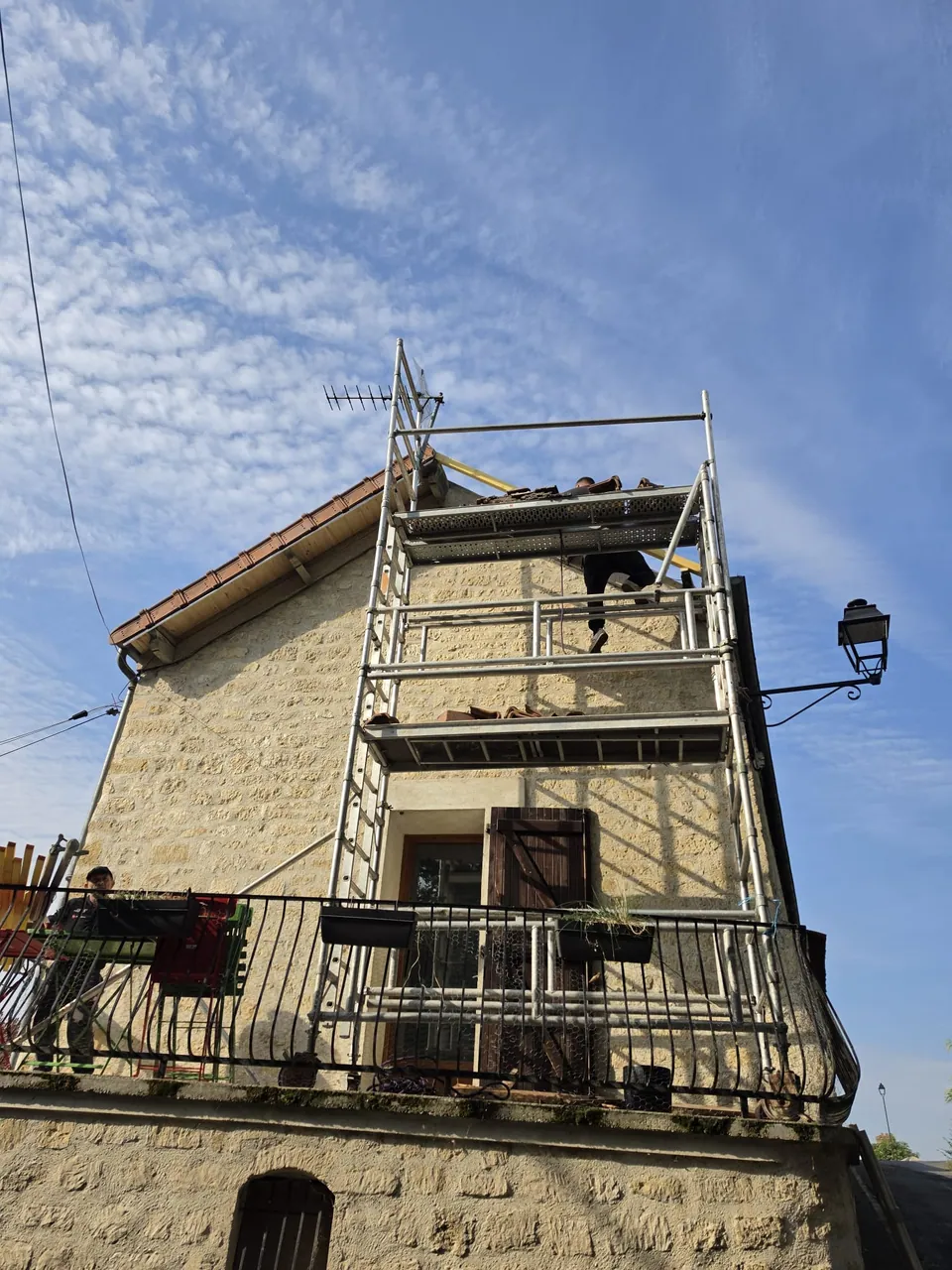 Pignon en pierre et échafaudage devant une toiture en tuiles ; commune à confirmer